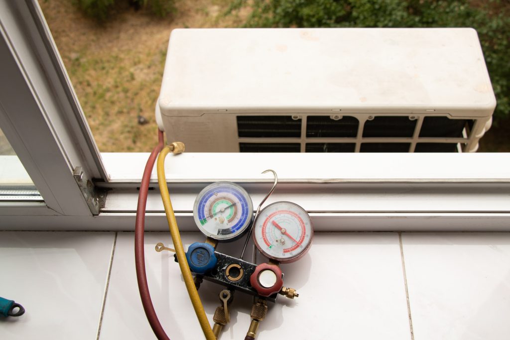 a two valve manometric manifold lies on the windowsill in the apartment and measures the pressure in the air conditioner at home, repair and diagnostics of the air conditioner